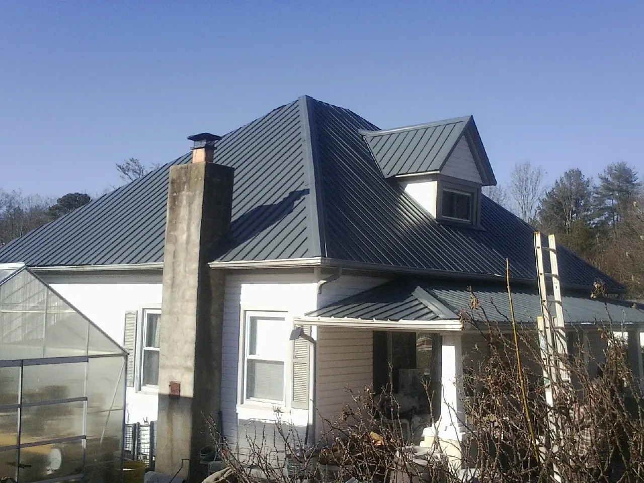 Dark blue standing seam metal roof on a white farmhouse with dormer — Slate & Tile Roof Repair by Roofing Brothers in Stinson Beach