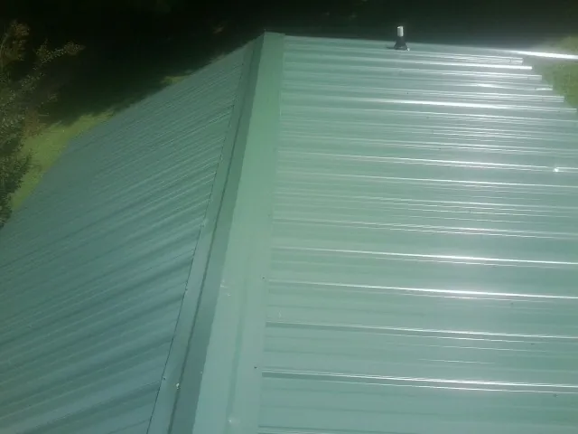 New green metal panels meeting at the ridge of a roof — Flat Roof Repair work by our crew in Stinson Beach