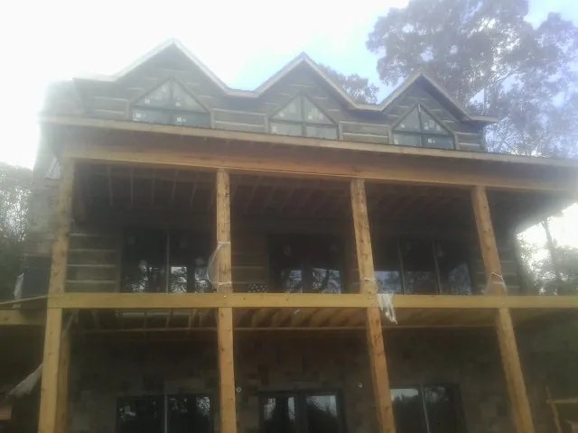 Dormers and porch framing on a large log home under construction — Roof Coating work by our crew in Stinson Beach