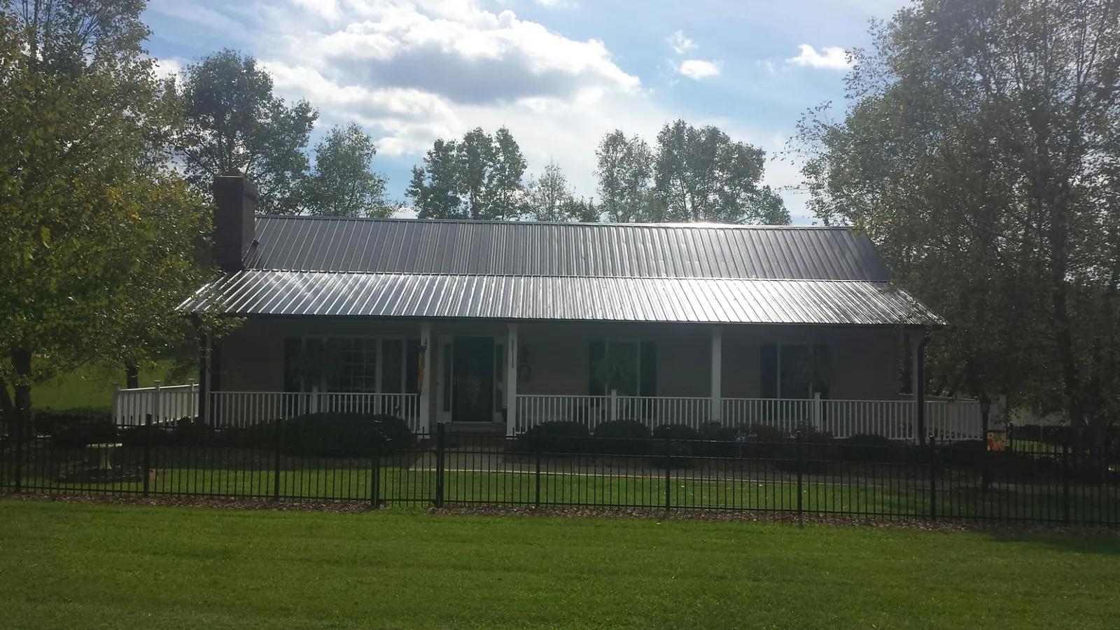 Gray metal roof on a brick ranch with a full width front porch — Gutter Guard Installation work by our crew in Stinson Beach
