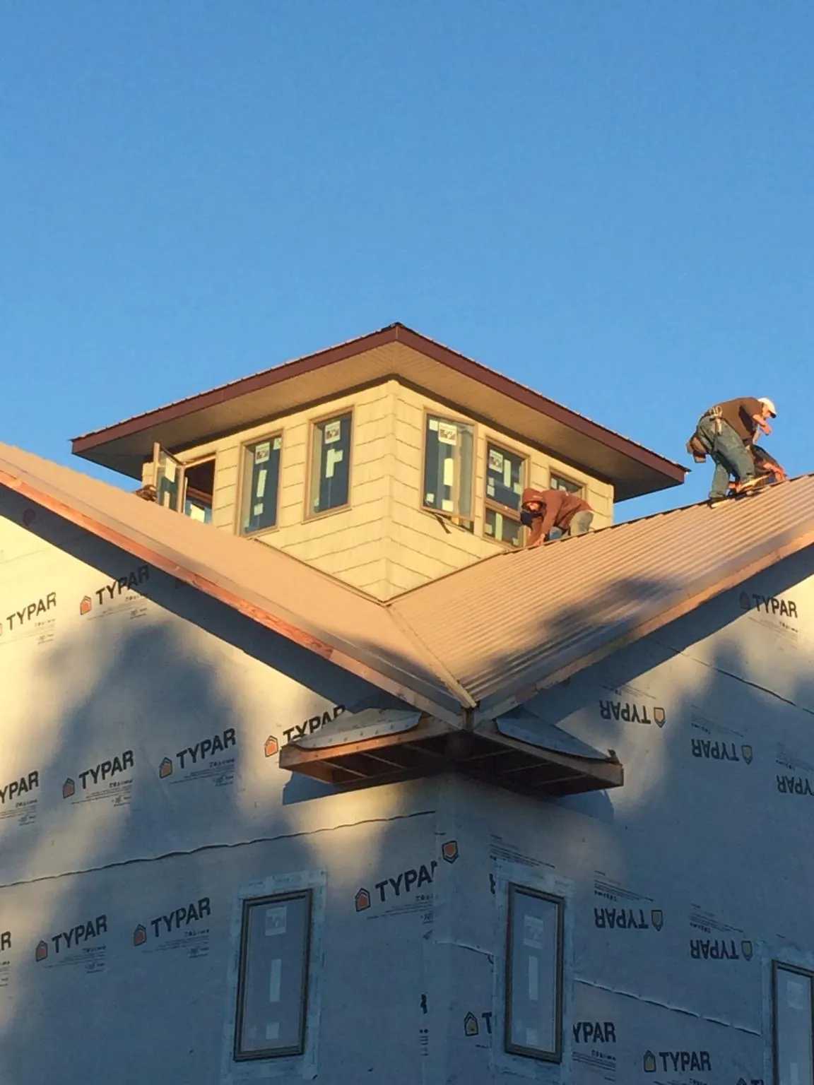 Roofers working around a rooftop cupola on a new metal roof at sunset — Roof Waterproofing in Stinson Beach by Roofing Brothers
